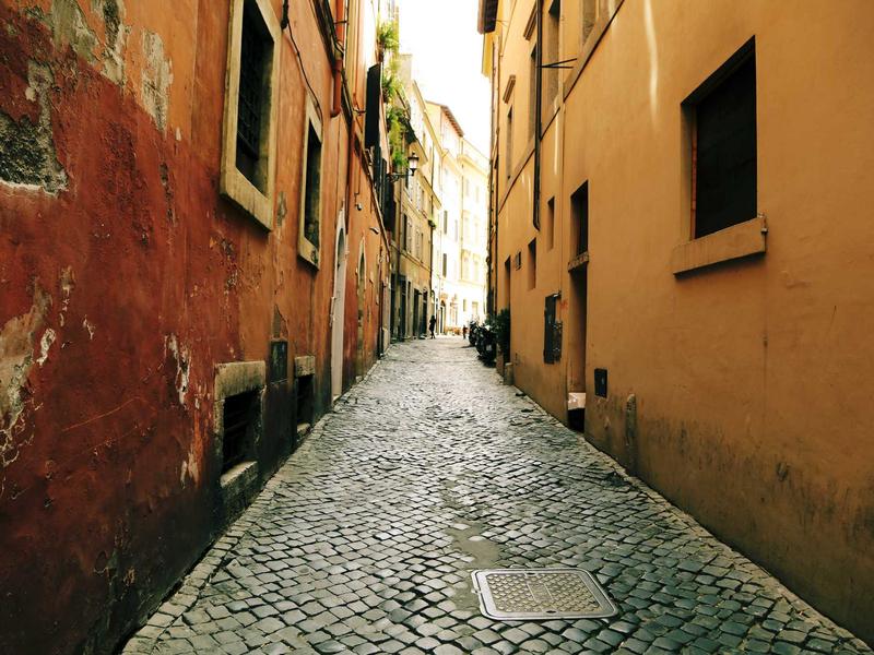 Ruelle pavée entre bâtiments anciens en Italie.